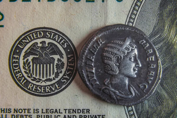 Une vieille pièce romaine repose sur un billet de 100 dollars — Photo