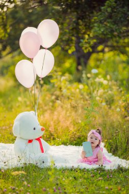 Battaniyenin üzerinde oturan telefonu olan bir kız.