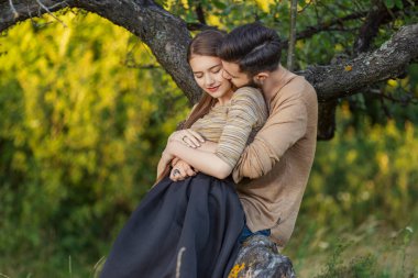 Bir ağacın yanında kucaklaşan çift.