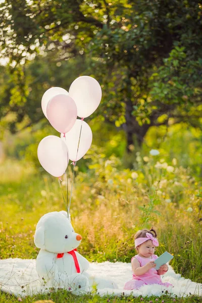 Battaniyenin üzerinde oturan telefonu olan bir kız.