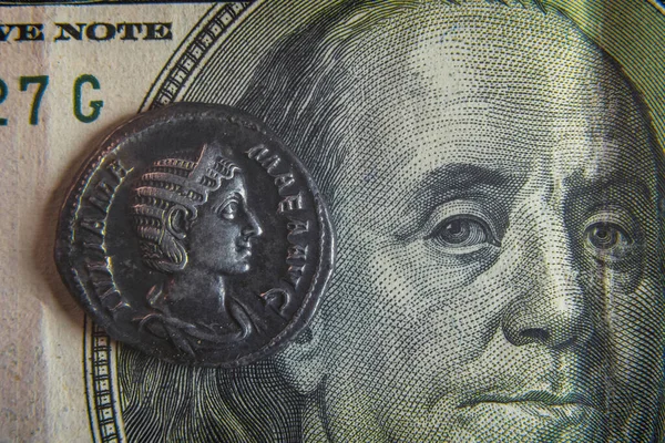 Una vieja moneda romana yace en un billete de 100 dólares —  Fotos de Stock