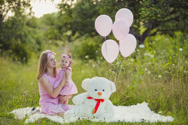 Pembe elbiseli ve pembe balonlu anne-kız.