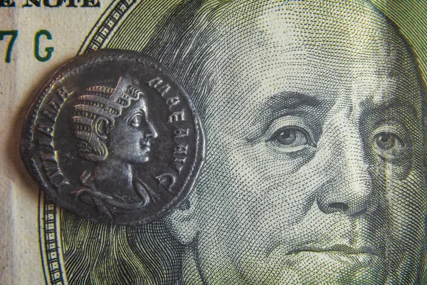 Egy régi római érme egy 100 dolláros bankjegyen fekszik. — Stock Fotó