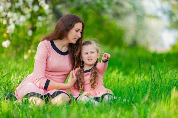 Mother and daughter sitting in green grass — Stock Photo, Image