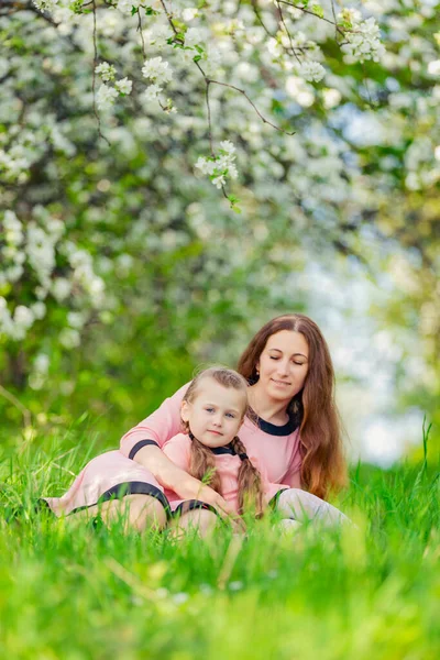Mother and daughter sitting in green grass — Foto de Stock