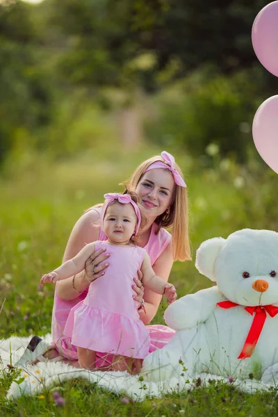 Moeder en dochter in roze jurken en roze ballonnen — Stockfoto