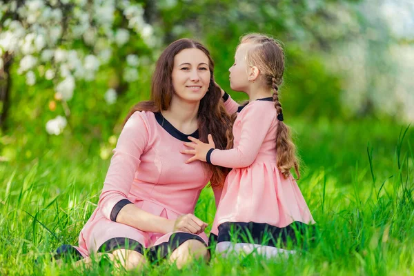 Mother and daughter sitting in green grass — Stock Photo, Image