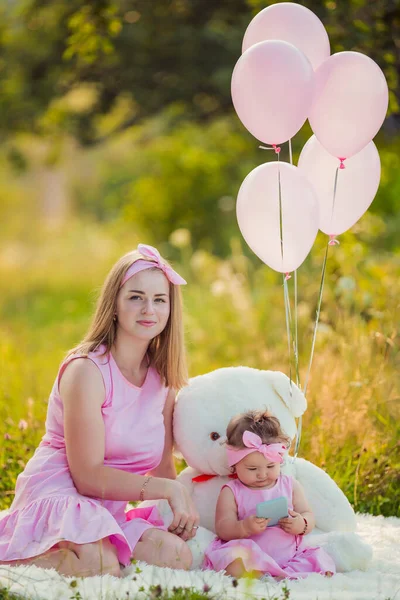 Mor och dotter i rosa klänningar och rosa ballonger — Stockfoto