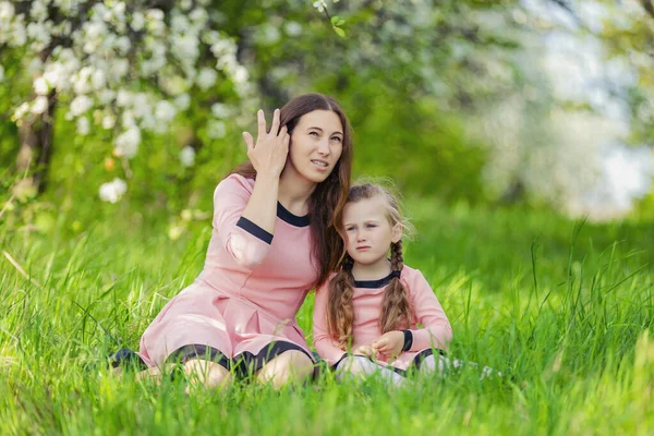 Anne ve kızı yeşil çimlerde oturuyor. — Stok fotoğraf
