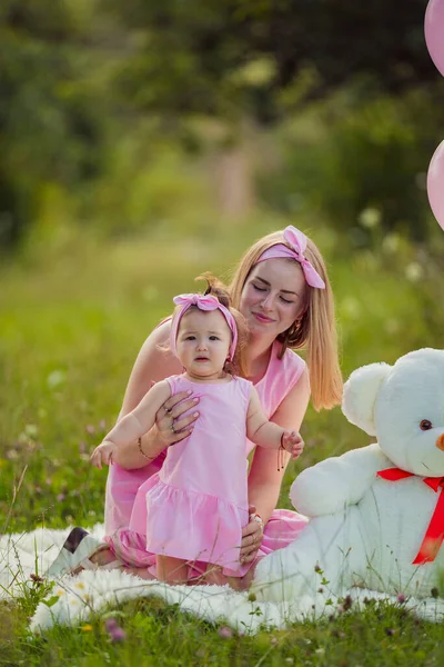 Pembe elbiseli ve pembe balonlu anne-kız.