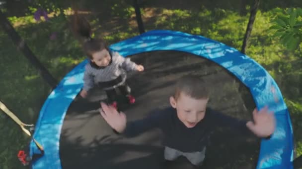 Δύο παιδιά διασκεδάζουν πηδώντας σε ένα τραμπολίνο. — Αρχείο Βίντεο