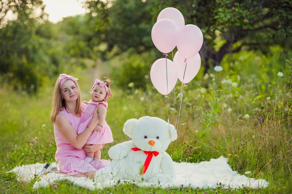 Pembe elbiseli ve pembe balonlu anne-kız.
