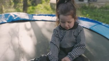 Kız trambolinde otururken telefona bakıyor.