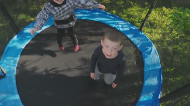 Két gyerek jó szórakozást a trambulinon ugráláshoz. — Stock videók