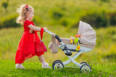 Kız bebeğini yuvarlıyor.