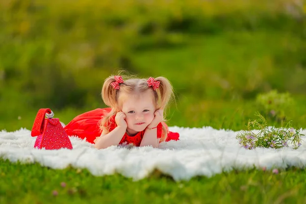 Girl in a red dress lies on a white blanket — Stockfoto