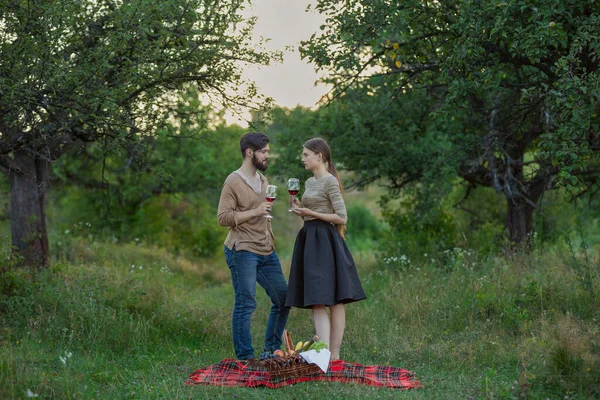 young couple drinking standing drinking wine from glasses being in nature