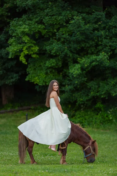 Chica Vestido Blanco Monta Pony Césped Verde —  Fotos de Stock