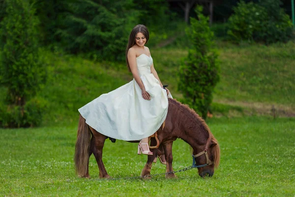 Menina Vestido Branco Monta Pônei Gramado Verde — Fotografia de Stock