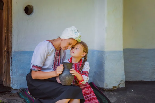 身着乌克兰民族服装的母女坐在一座老房子旁边 — 图库照片