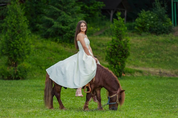 Menina Vestido Branco Monta Pônei Gramado Verde — Fotografia de Stock