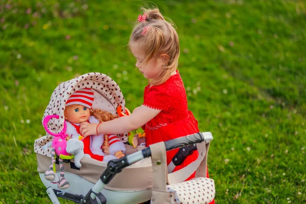 Fille Joue Avec Poupée Qui Est Assis Dans Une Poussette — Photo