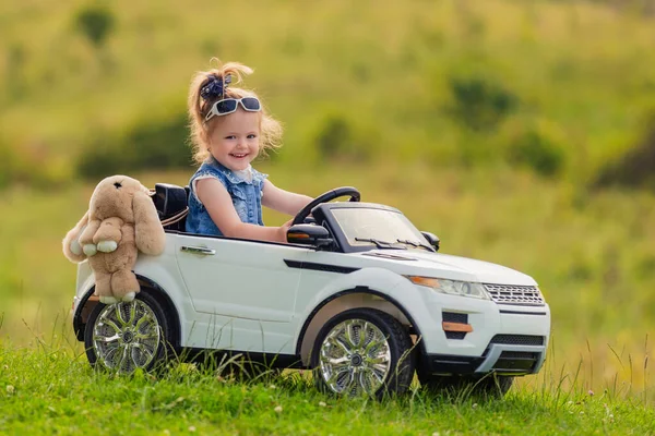 緑の芝生の上の子供用車に女の子が乗っています — ストック写真