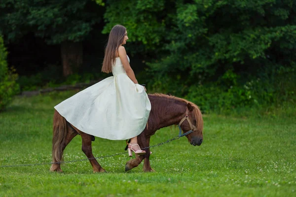 Chica Vestido Blanco Monta Pony Césped Verde — Foto de Stock