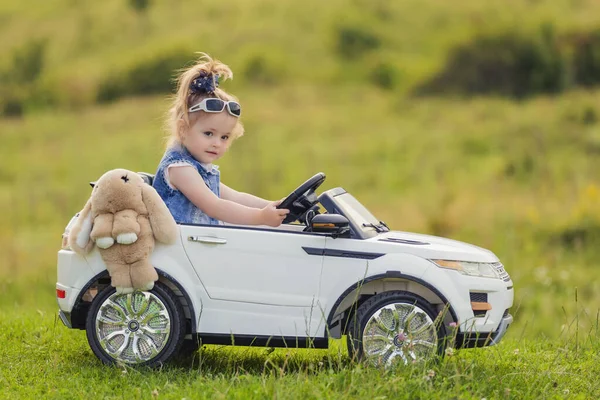 緑の芝生の上の子供用車に女の子が乗っています — ストック写真