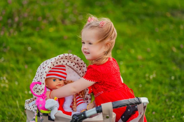 Meisje Speelt Met Haar Pop Die Zit Een Speelgoed Wandelwagen — Stockfoto