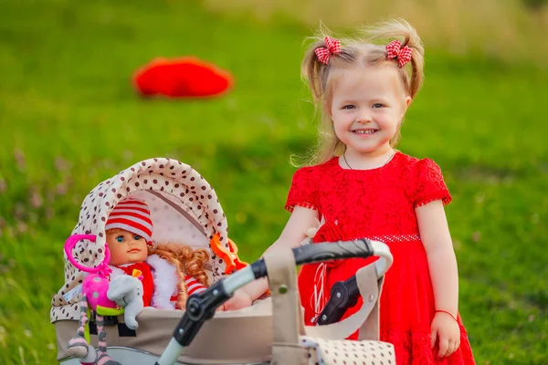 girl playing with a doll in a stroller in nature