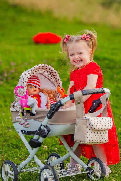 girl playing with a doll in a stroller in nature