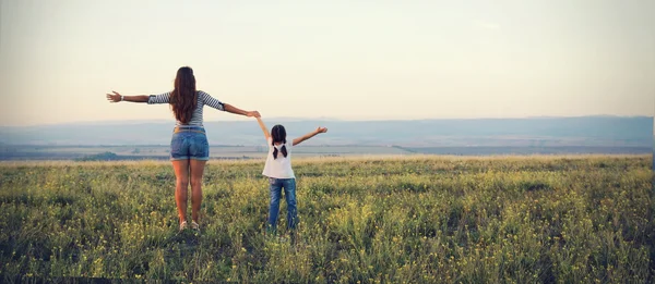 Mom and daughter go off into the distance on a beautiful meadow — Stock Photo, Image