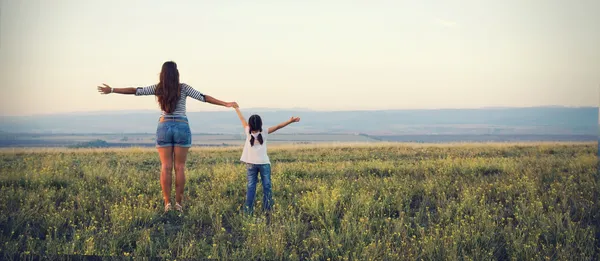 Mamma e figlia vanno in lontananza su un bellissimo prato Foto Stock