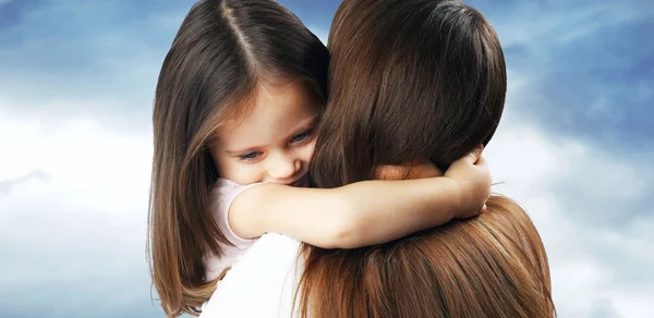 Kleines Mädchen mit schönem Haar umarmt seine Mutter — Stockfoto