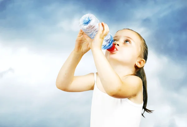 Une petite fille sucrée boit de l'eau d'une bouteille Image En Vente