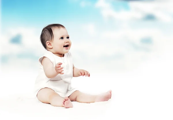 Lindo bebé feliz en el suelo sobre un fondo de cielo Imágenes de stock libres de derechos