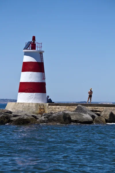Zwei Personen bewundern das Meer neben einem kleinen Leuchtturm — Stockfoto