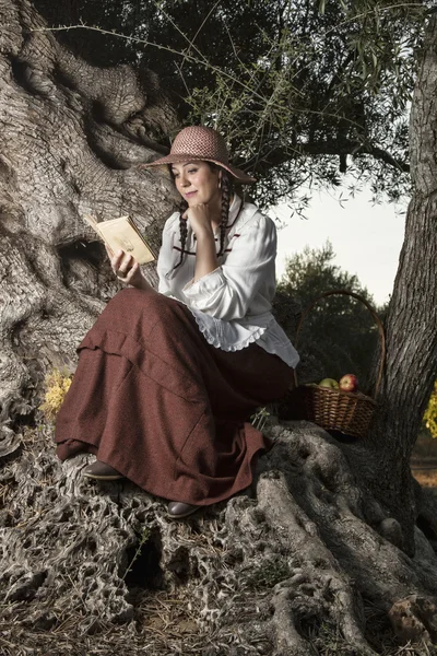 Hermosa chica en el campo a la sombra leyendo un libro —  Fotos de Stock