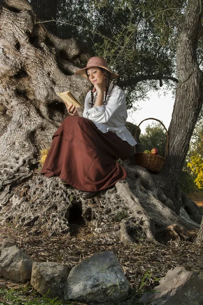 Hermosa chica en el campo a la sombra leyendo un libro — Foto de Stock