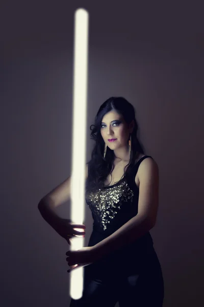 Krásná dívka v tmavé kožené oblečení drží světelné trubice — Stock fotografie
