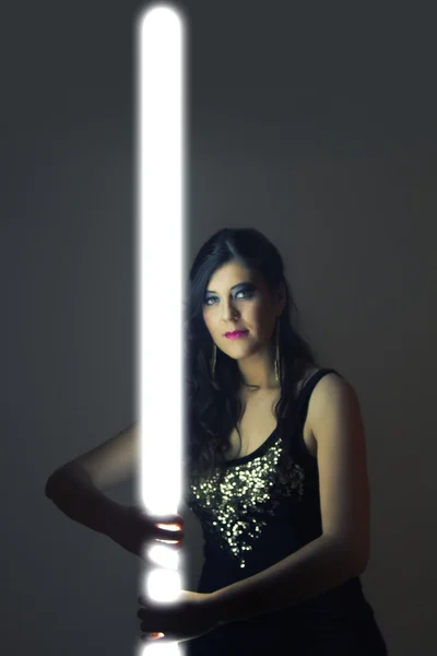 Gadis cantik dengan pakaian kulit gelap memegang tabung cahaya — Stok Foto