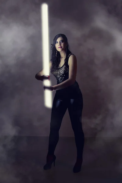 Hermosa chica en ropa de cuero oscuro sosteniendo un tubo de luz —  Fotos de Stock