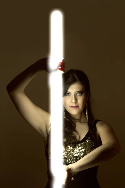 Hermosa chica en ropa de cuero oscuro sosteniendo un tubo de luz —  Fotos de Stock