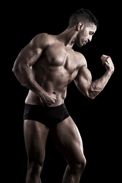 Hombre musculoso sobre un fondo negro — Foto de Stock