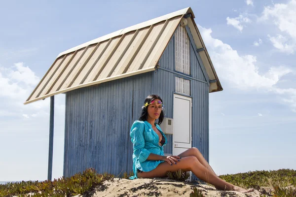 Krásná dívka na pláži vedle modré dřevník — Stock fotografie