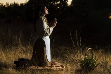classical girl praying on the countryside clipart