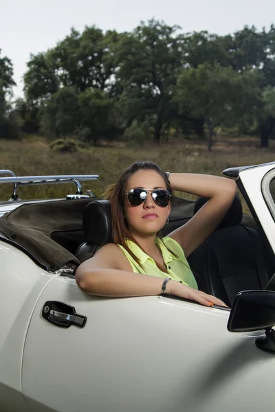 Mooie vrouw die zich voordeed op een witte converteerbare auto — Stockfoto