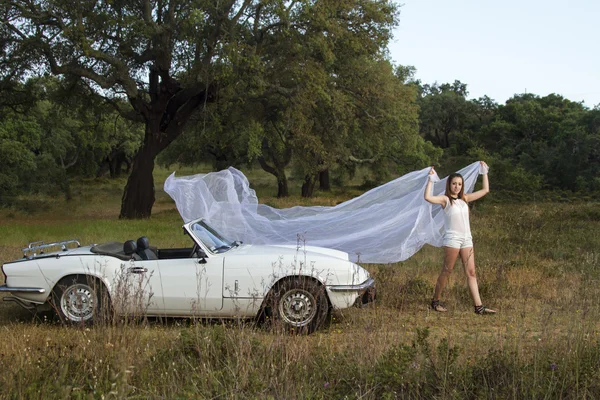 美丽的女人，摆上一辆白色的可转换轿车 — 图库照片
