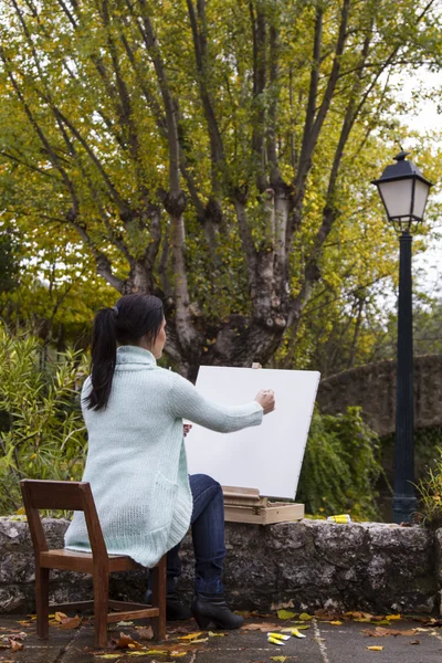 Jonge vrouw schilderij op een park — Stockfoto